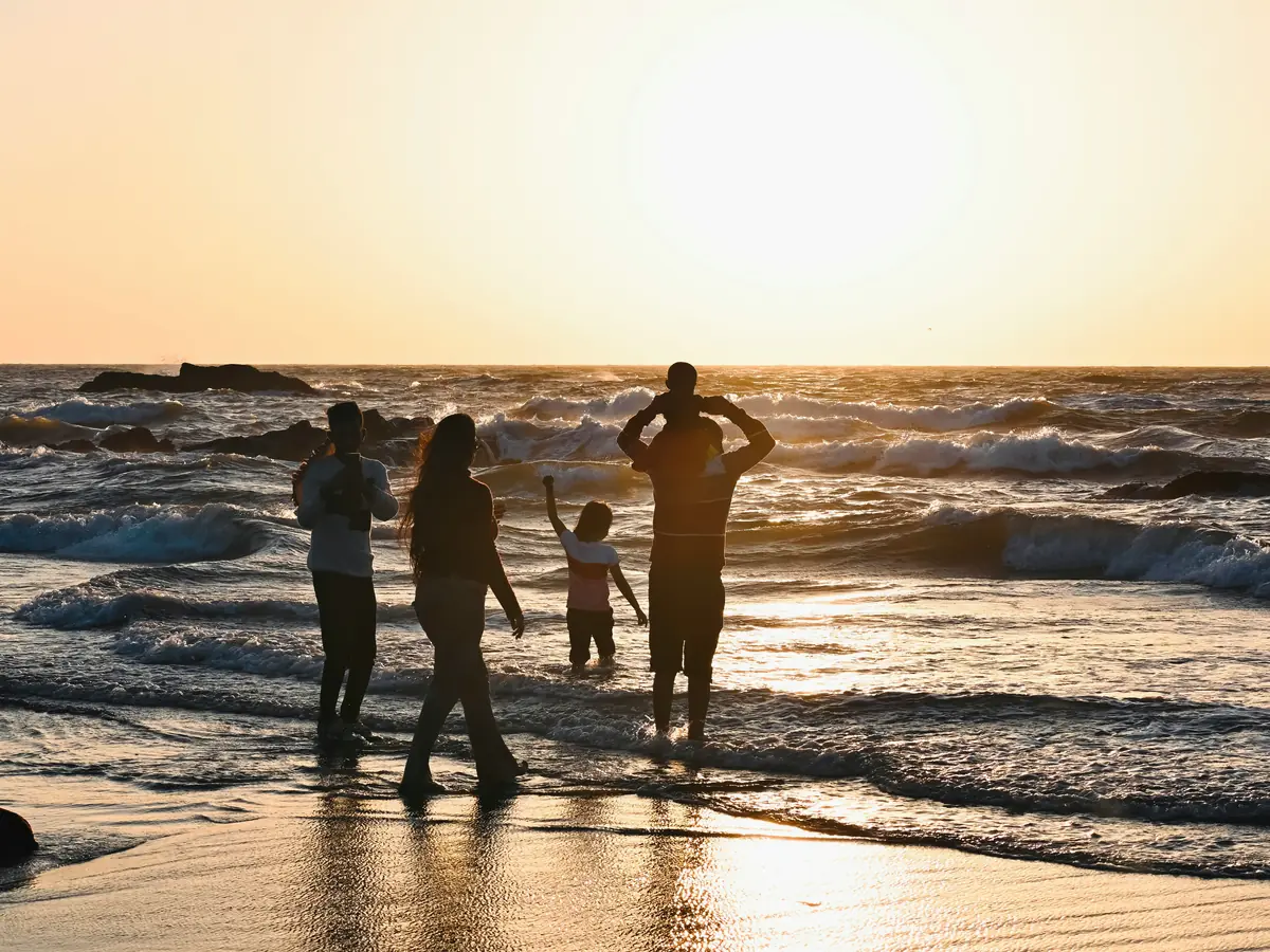 Familia caminando por la orilla del mar al atardecer